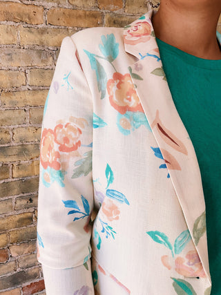 Floral-patterned jacket worn by a person against a brick wall.