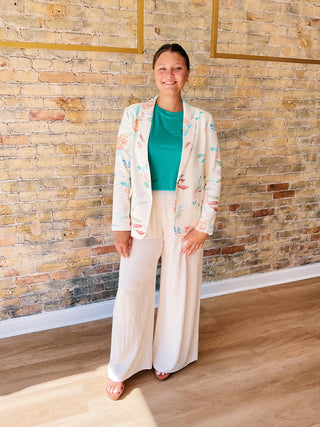 Woman in a light-colored outfit standing against a brick wall.