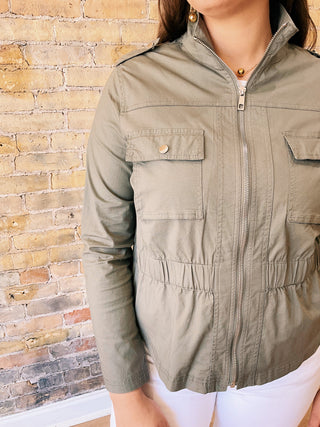 Person wearing a green jacket against a brick wall