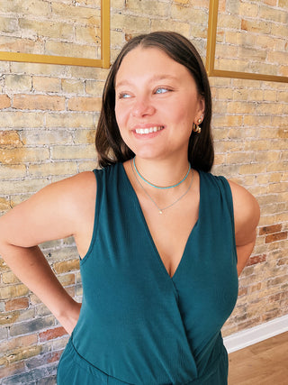 Model wearing teal Samantha Jumpsuit with wide legs and sneakers in boutique setting