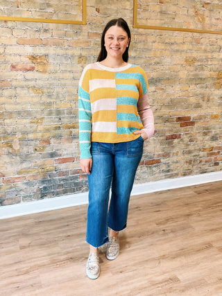 model is wearing a striped sweater, cropped jeans and sneakers.