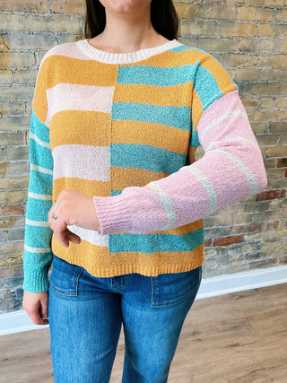 model is wearing a striped sweater, showing details on sleeves.