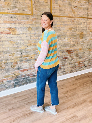 model is wearing a striped sweater, cropped jeans showing back.