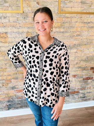 Woman wearing a leopard print blouse with a brick wall background