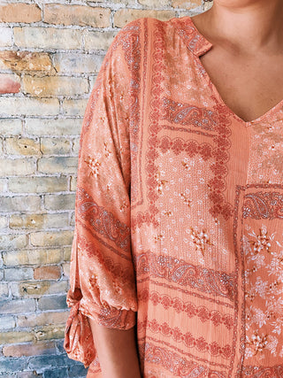 woman wearing a boho paisley print blouse with 7/8 sleeves and relaxed fit. 

