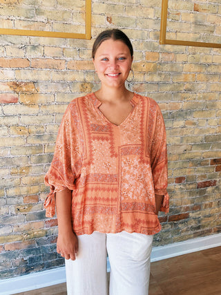 woman wearing a boho paisley print blouse with 7/8 sleeves and relaxed fit. 