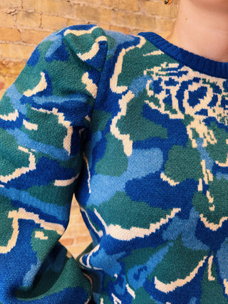 Close-up of a blue and green patterned sweater sleeve against a wooden background