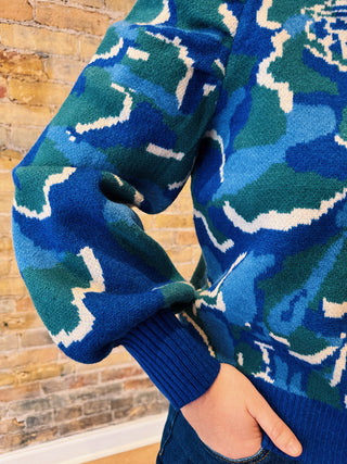 Close-up of a blue patterned sweater with a brick wall background