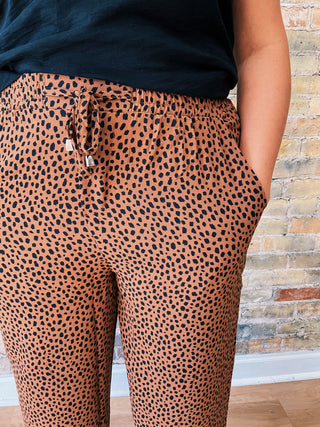 Detailed close-up of Callie Pants waistband and drawstring with silver tips, showing brown and black spotted animal print fabric texture.