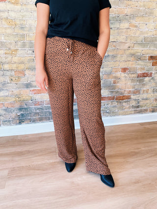 Close-up of Callie Pants showing brown and black animal print fabric with drawstring elastic waistband and side pockets.