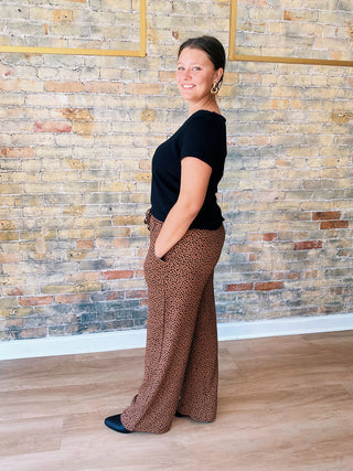 Side view of model wearing Callie Pants, showcasing wide-leg silhouette and relaxed fit in brown animal print pattern.