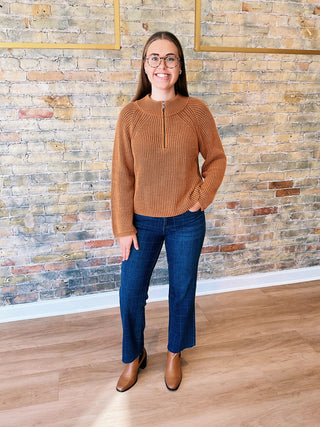 Woman wearing the Ella Sweater, a high neck zip-up ribbed knit sweater styled with denim for a polished casual look.