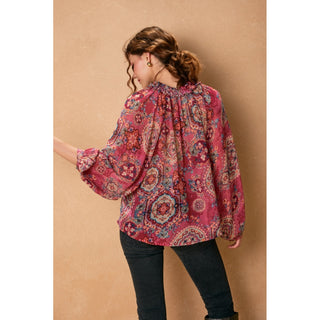 Woman wearing a pink patterned blouse against a beige background