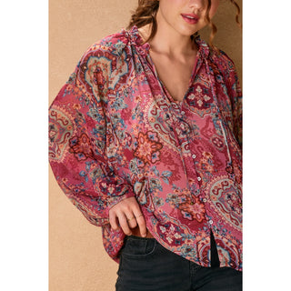 Woman wearing a pink floral blouse against a beige background