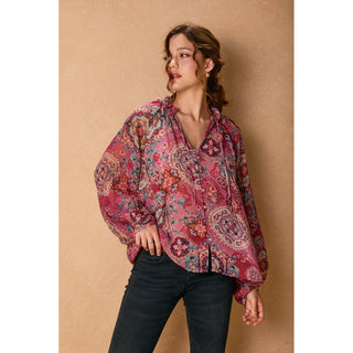 Woman wearing a patterned blouse against a beige background