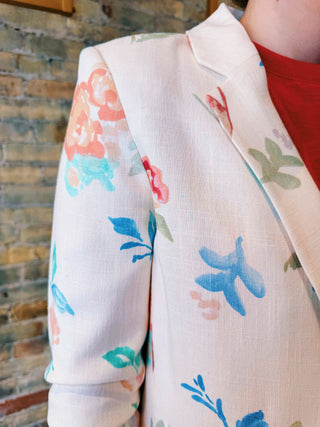 Floral-patterned blazer worn by a person against a stone wall background