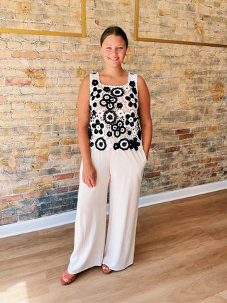 Woman wearing a contrast floral crochet sleeveless top in poivre with scalloped hem.