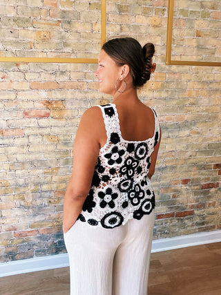 Woman wearing a contrast floral crochet sleeveless top in poivre with scalloped hem detail back details.


