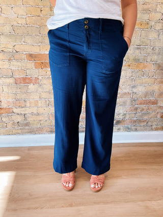 Person wearing blue pants standing against a brick wall.