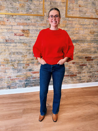 Woman wearing tomato red batwing sleeve sweater with jeans