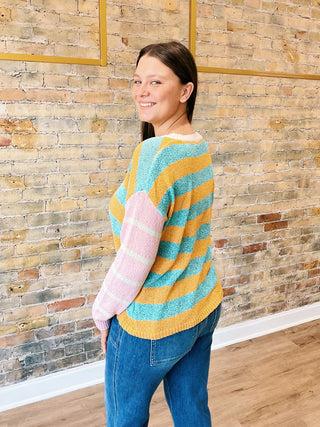 model is wearing a striped sweater, cropped jeans showing back.