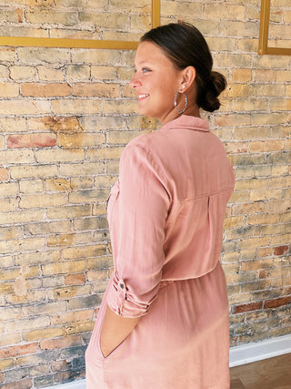 Woman wearing a pink dress against a brick wall